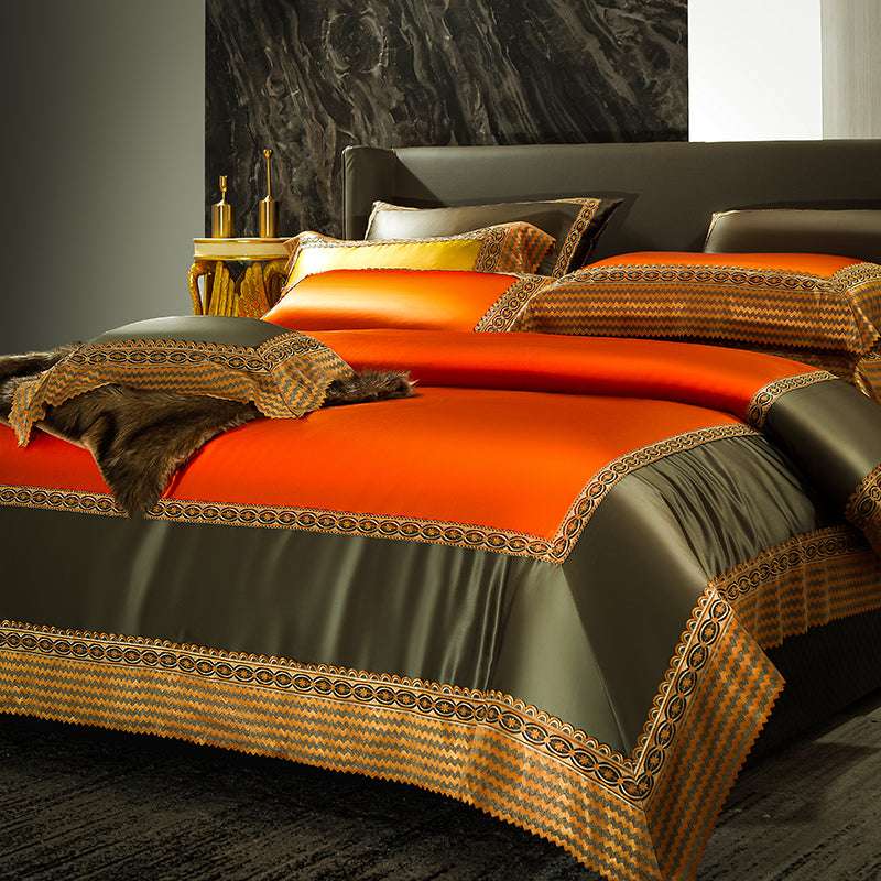 Luxurious bedding set featuring vibrant orange and olive green hues with intricate embroidered details along the edges. A decorative faux fur throw and matching pillow complete the elegant and bold look.