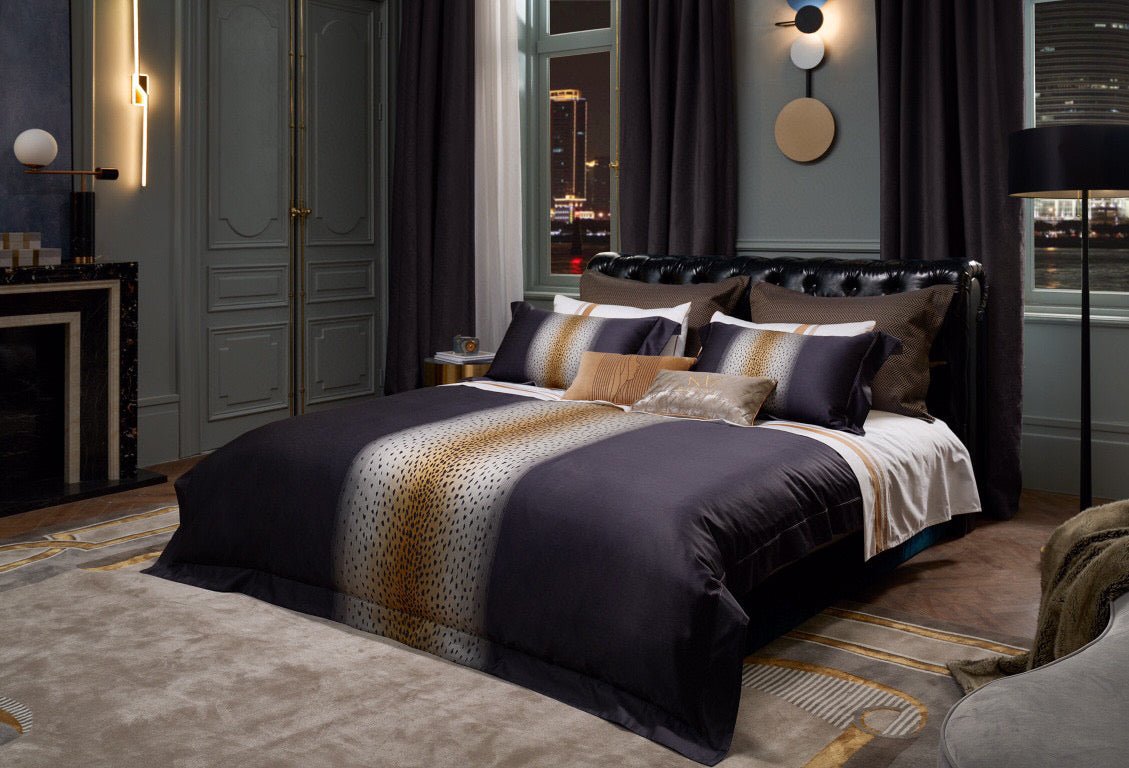 Luxurious bedding set crafted from Egyptian cotton, featuring a central leopard print-inspired design in gold and black tones. Coordinated with plush pillows and accent cushions in metallic and textured patterns, styled in a sophisticated bedroom with a nighttime cityscape view through tall windows. Decorated with modern wall art and elegant furnishings, emphasizing contemporary elegance.