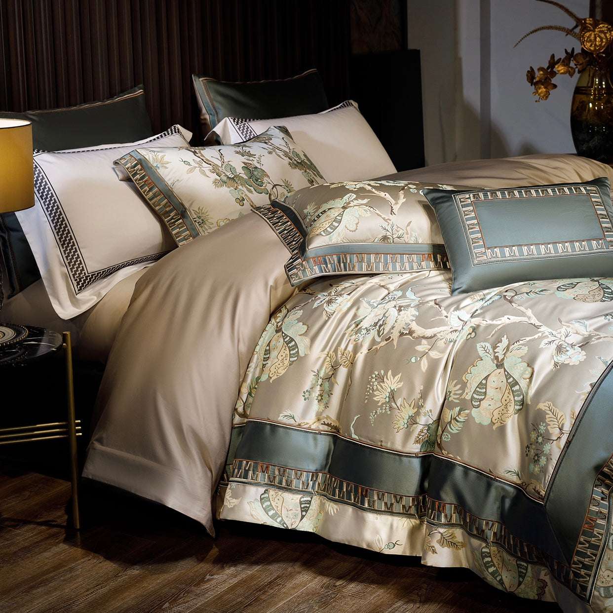This close-up showcases a luxurious bedding set featuring an intricate design of floral and butterfly motifs in shades of beige and sage green, accented with elegant geometric borders. The duvet cover and pillow shams exhibit a harmonious blend of patterns, complemented by a satin-like sheen that adds a touch of opulence. The bed is accessorized with a decorative rectangular pillow and a neatly layered arrangement of linens, creating a cozy yet sophisticated atmosphere. The dark-paneled headboard and muted
