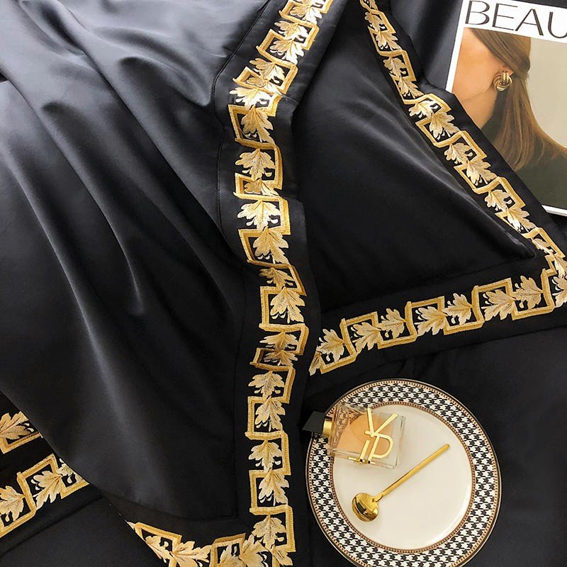 Detailed view of the black Egyptian cotton fabric adorned with intricate gold embroidery, accompanied by a luxury plate and golden accents, highlighting the set's opulence.