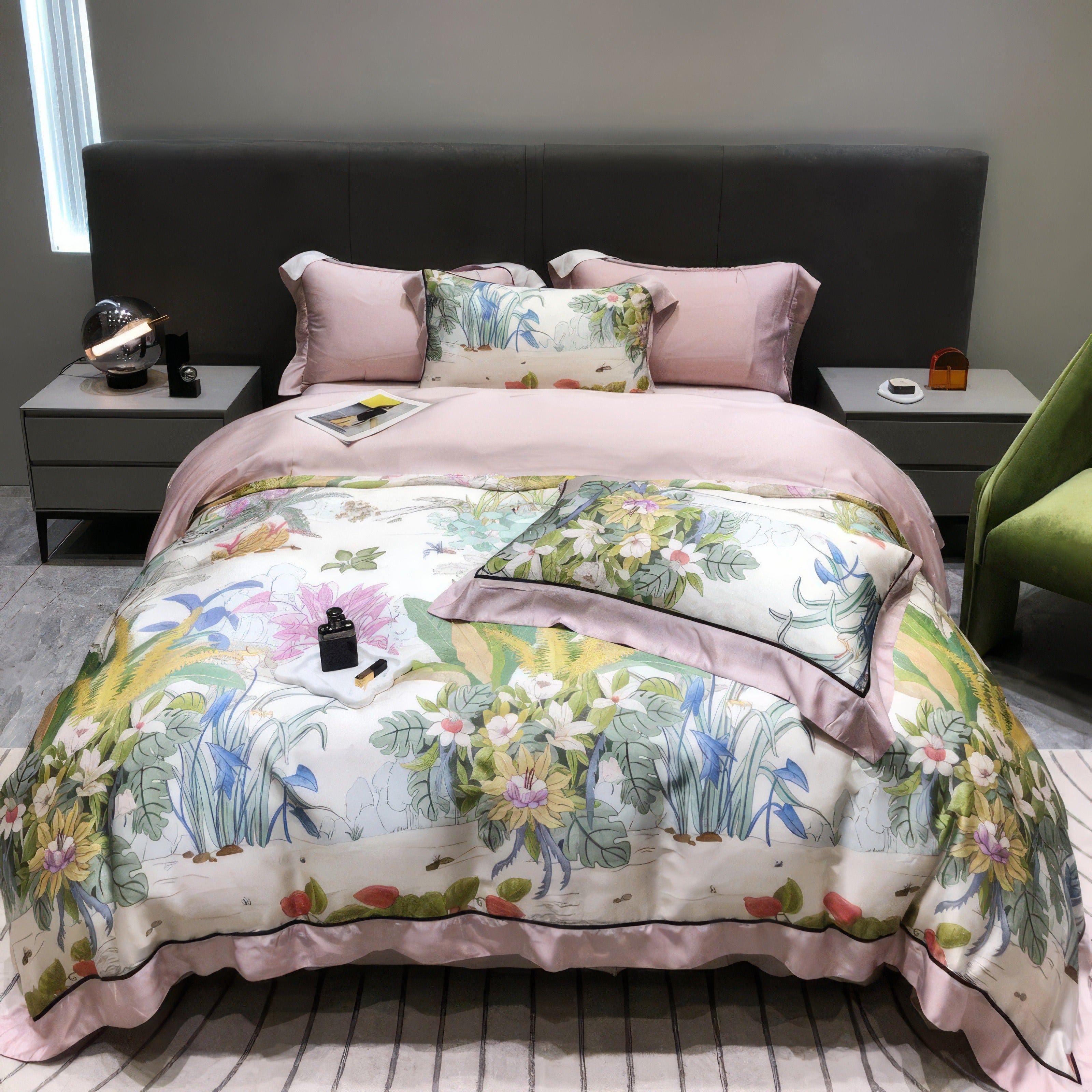 Luxury bedding set crafted from Egyptian cotton, featuring a soft pink duvet cover complemented by a vibrant floral-patterned comforter adorned with lush botanical illustrations in green, yellow, and white tones. Includes matching pillowcases with elegant floral designs and solid pink accents. The modern setup features a grey upholstered headboard, bedside tables, and decor items, creating a serene and sophisticated bedroom ambiance.