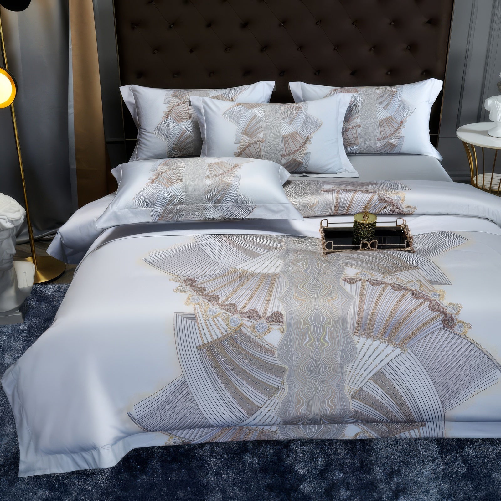 Elegant white bedding set with intricate fan-like patterns in beige and gray hues, complemented by matching pillowcases and a stylish tufted headboard, creating a refined and luxurious bedroom ambiance. A decorative tray with a green candle adds a sophisticated touch.