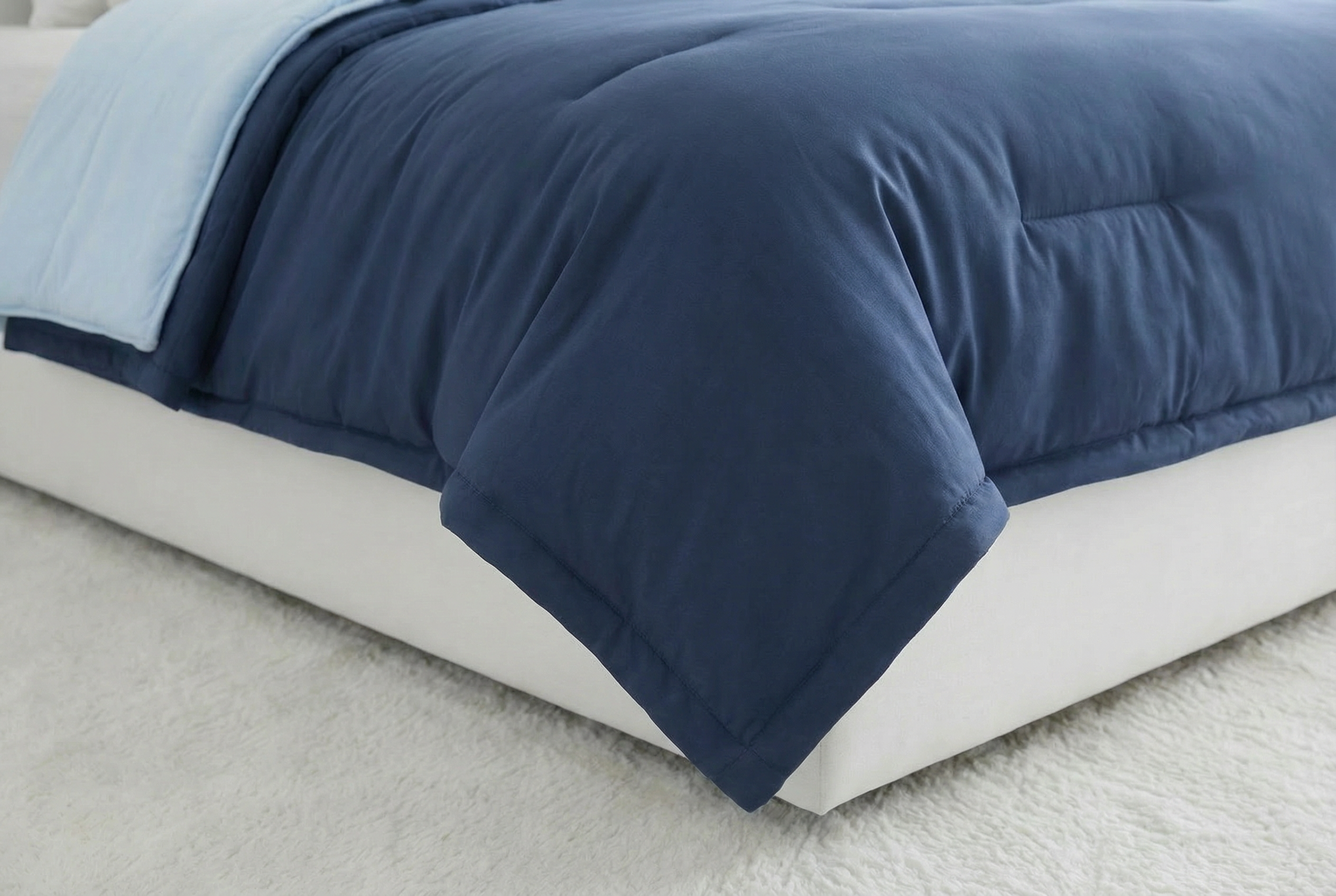 Blue comforter on a bed with a light gray background