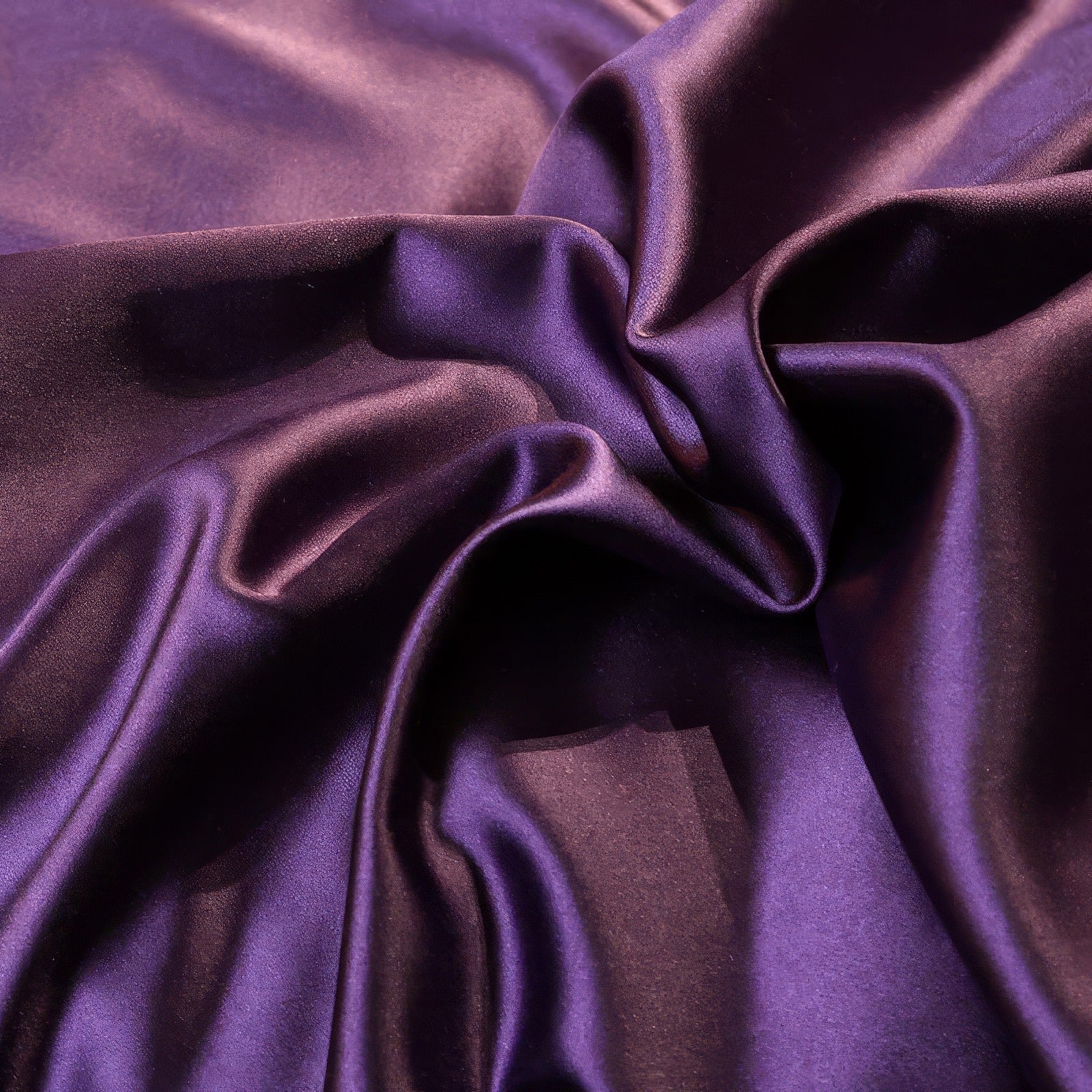 Close-up of smooth, rich purple satin fabric with gentle folds and a subtle sheen.