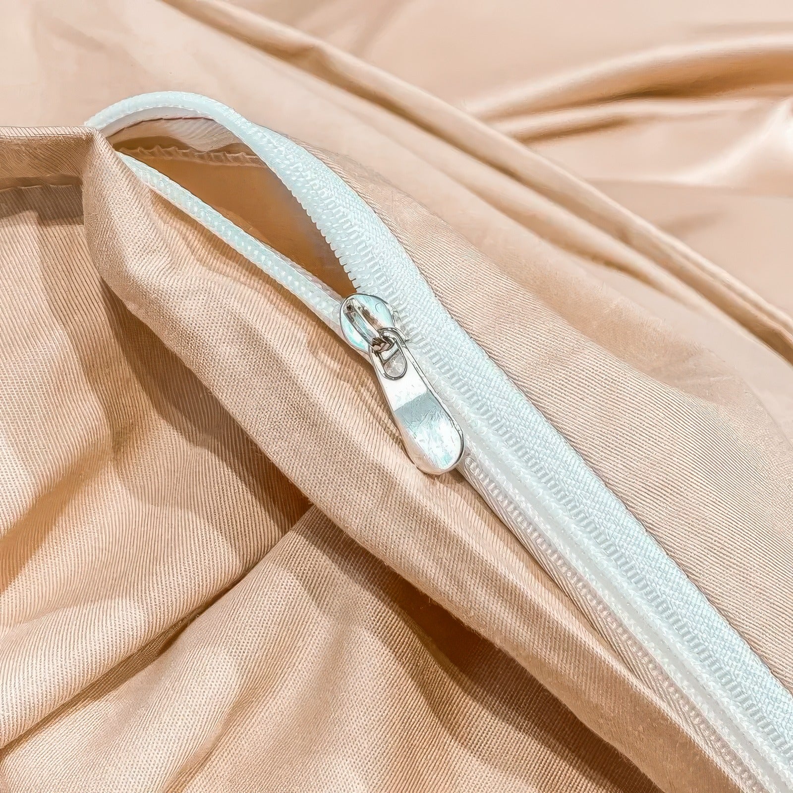 A close-up of a golden beige duvet cover featuring a hidden zipper closure for a seamless and elegant appearance. The zipper, in a contrasting white, provides a secure and durable fastening, blending functionality with style. The smooth fabric enhances the luxurious feel of the bedding.

