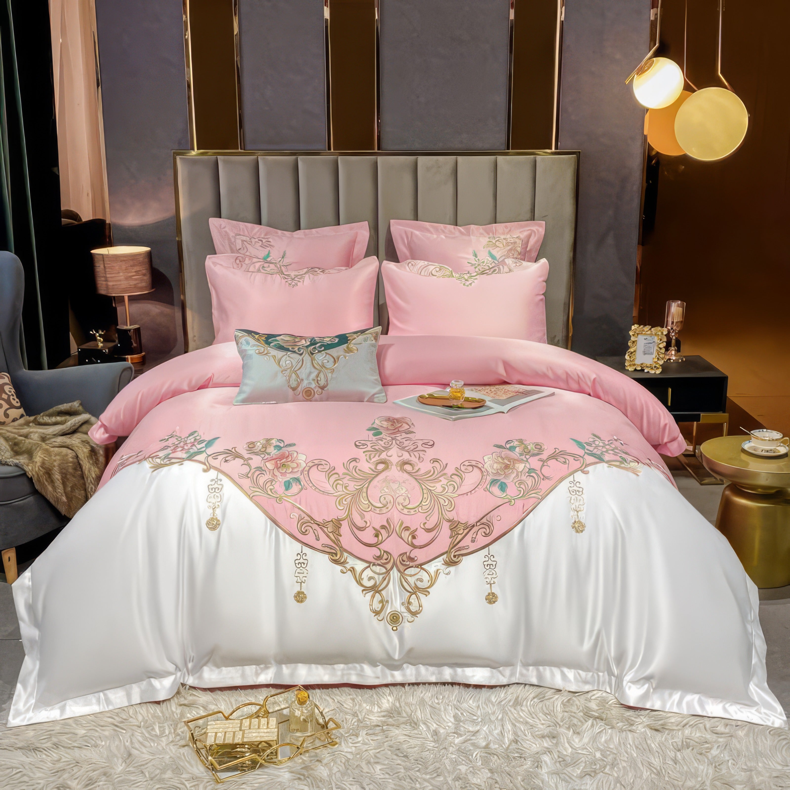 This luxurious bedding set features a pastel pink duvet cover adorned with intricate embroidery in golden and floral accents. Complemented by a white border at the bottom, the set includes matching pillowcases and decorative pillows. The backdrop of a modern upholstered headboard and elegant lighting enhances the opulent aesthetic.

