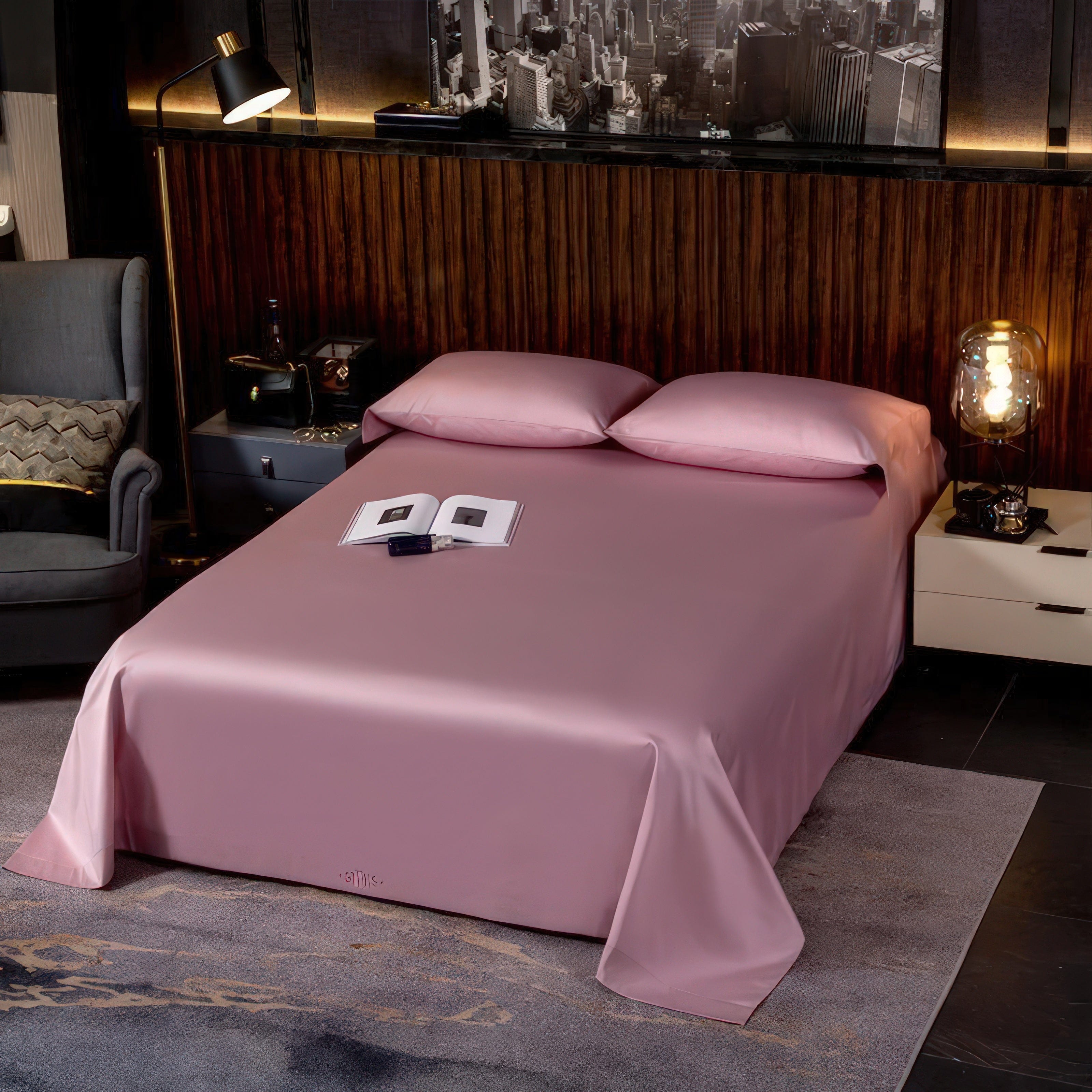 A modern bedroom with a clean and minimal aesthetic, showcasing soft pink bedding neatly arranged on the bed. The room features a sophisticated wooden-paneled wall, complemented by a contemporary armchair and ambient lighting. A black-and-white cityscape artwork adds an urban touch to the backdrop, while a book and phone placed on the bed introduce a cozy and relaxed vibe.

