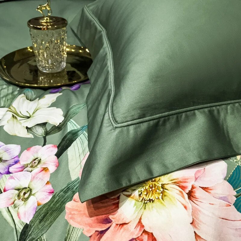 A close-up view of a solid green Egyptian cotton pillowcase paired with a floral bedspread, showcasing soft pink, purple, and white flowers with green foliage. The crisp detailing of the pillow edges contrasts beautifully with the vibrant floral accents, complemented by a decorative glass and gold tray nearby.

