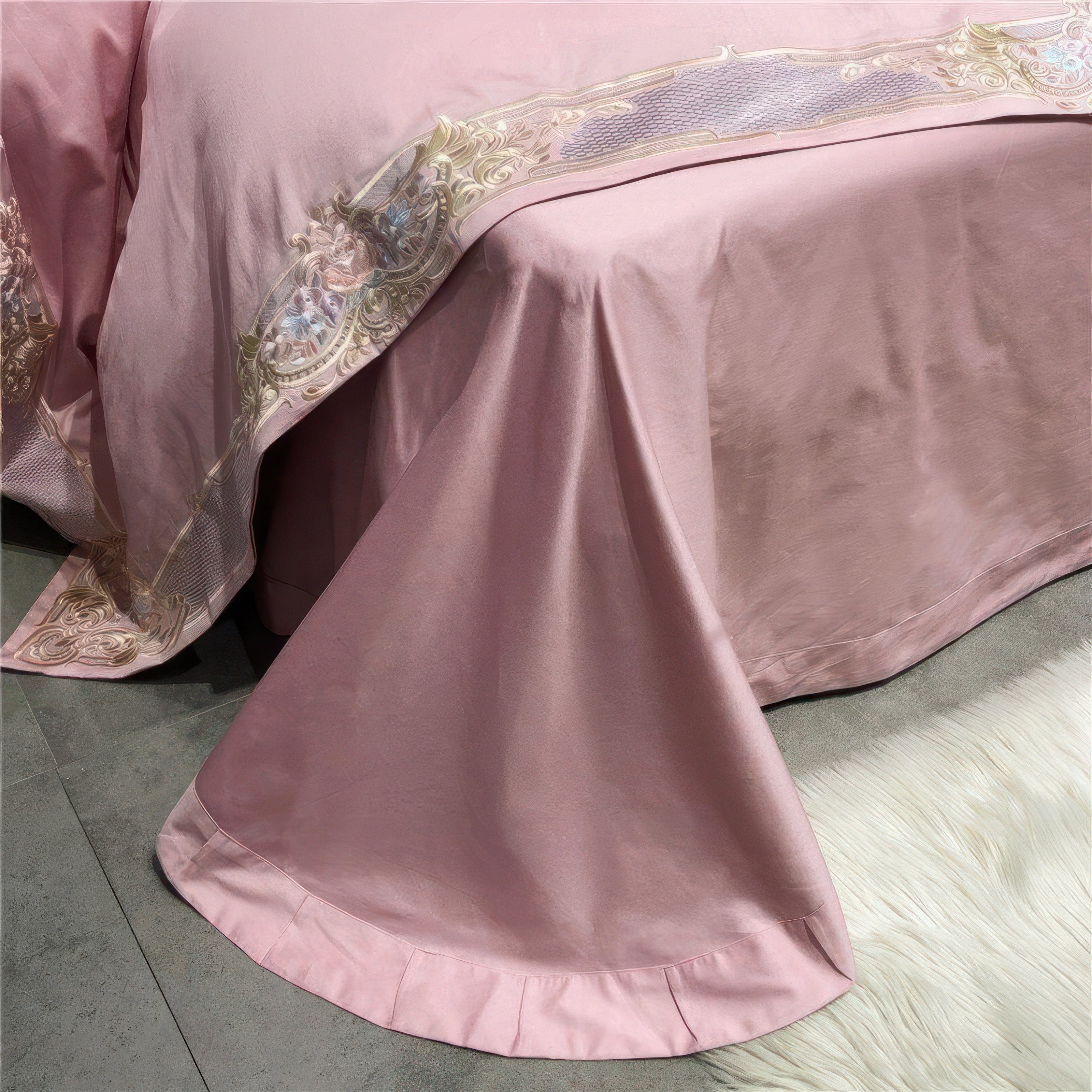 A close-up view of a pink bed skirt adorned with ornate embroidery in pastel tones of gold and blue. The fabric drapes gracefully over the bed edge, showcasing its silky texture and delicate craftsmanship. The scene is complemented by a soft white rug on the floor, enhancing the luxurious and cozy ambiance.

