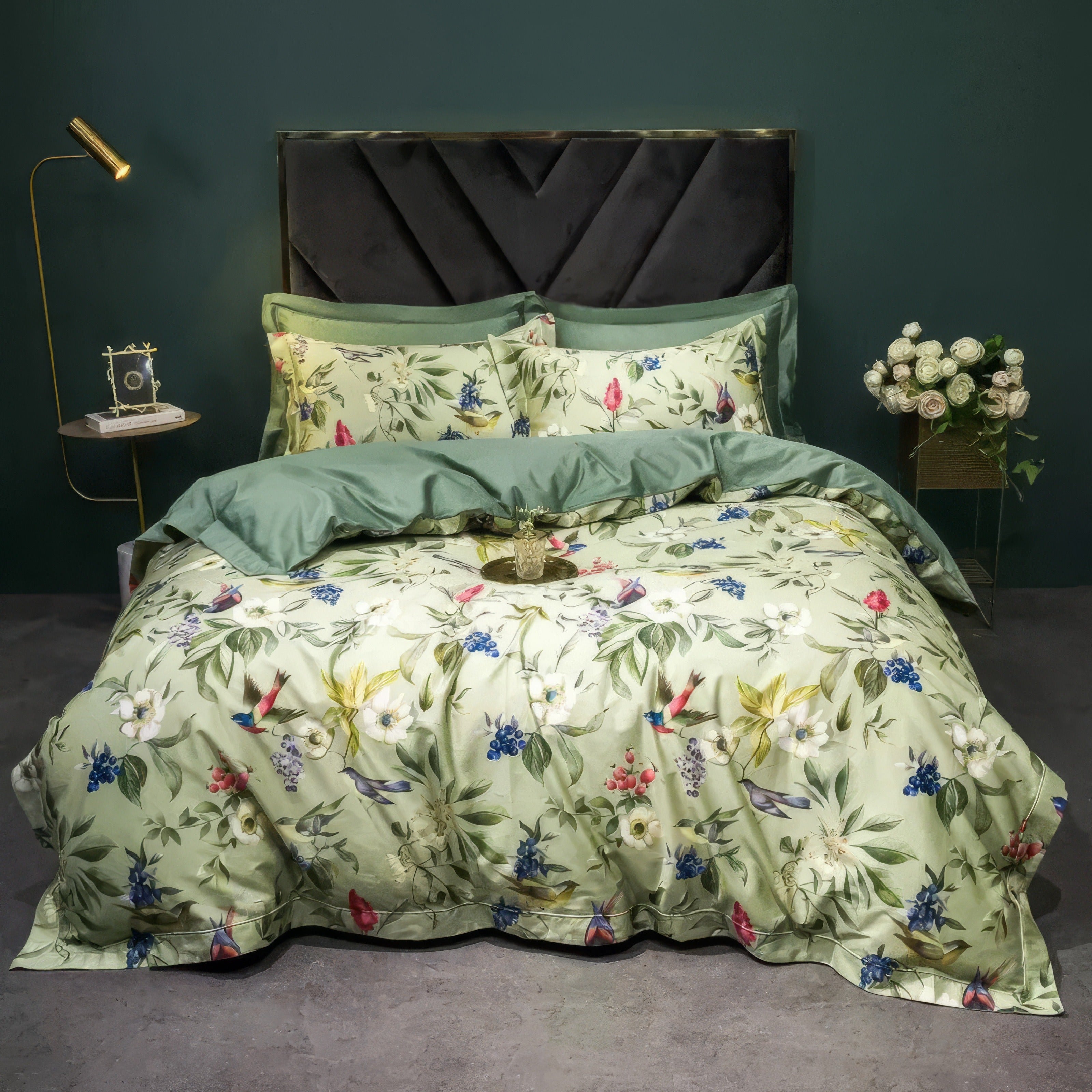 A bedding set featuring a floral pattern on a light green background, accented with vibrant hues of blue, pink, and red, paired with solid green pillowcases and a matching duvet cover, arranged in an elegant bedroom setting with a modern dark green backdrop.

