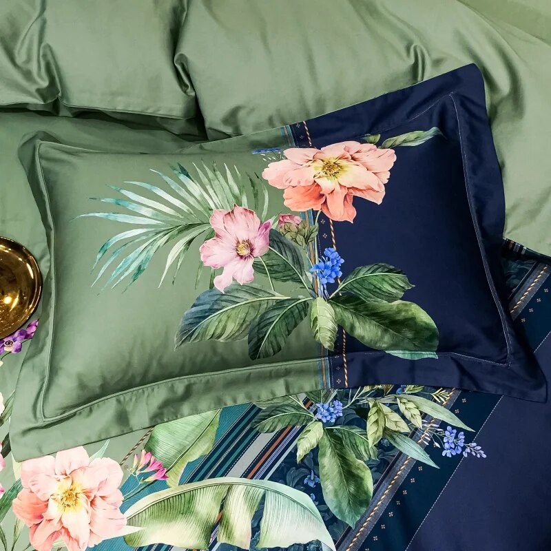 A vibrant pillowcase made of Egyptian cotton, featuring a striking floral design with large pink and peach blooms, green foliage, and blue accents set against a deep navy background. The rich details and soft textures create an elegant and refreshing aesthetic, complemented by the surrounding green bedding.

