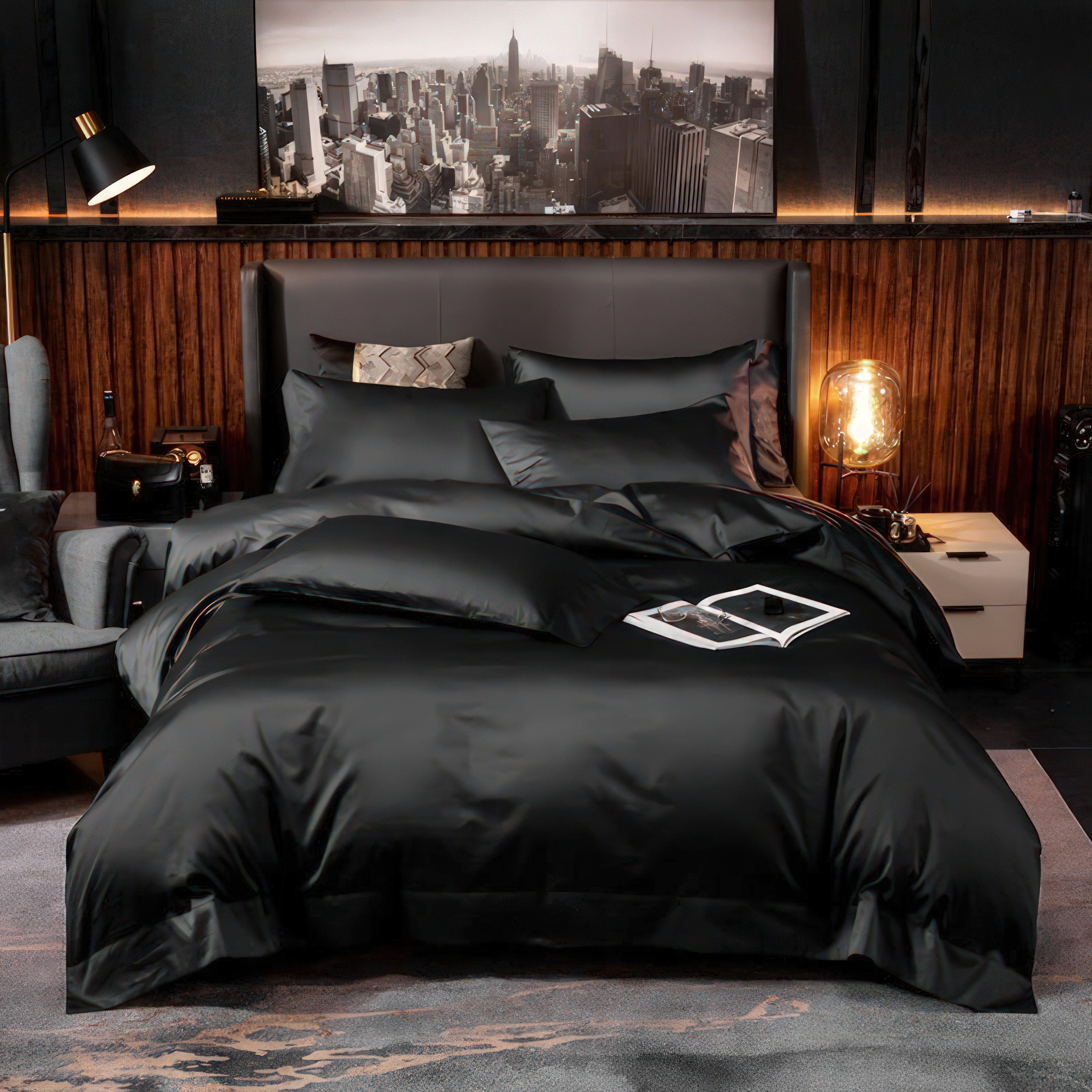 A stunning bedroom setup featuring a luxurious black bedding set with a smooth and silky texture. The bed is surrounded by warm lighting, modern decor elements, and a sophisticated cityscape wall art above the headboard. This setup exudes elegance and contemporary luxury.

