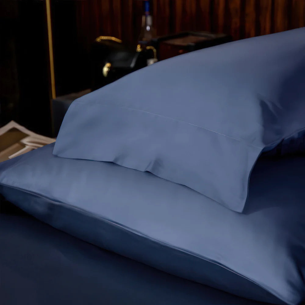 Close-up of two blue satin pillowcases stacked, highlighting their smooth, luxurious fabric and neatly stitched seams.

