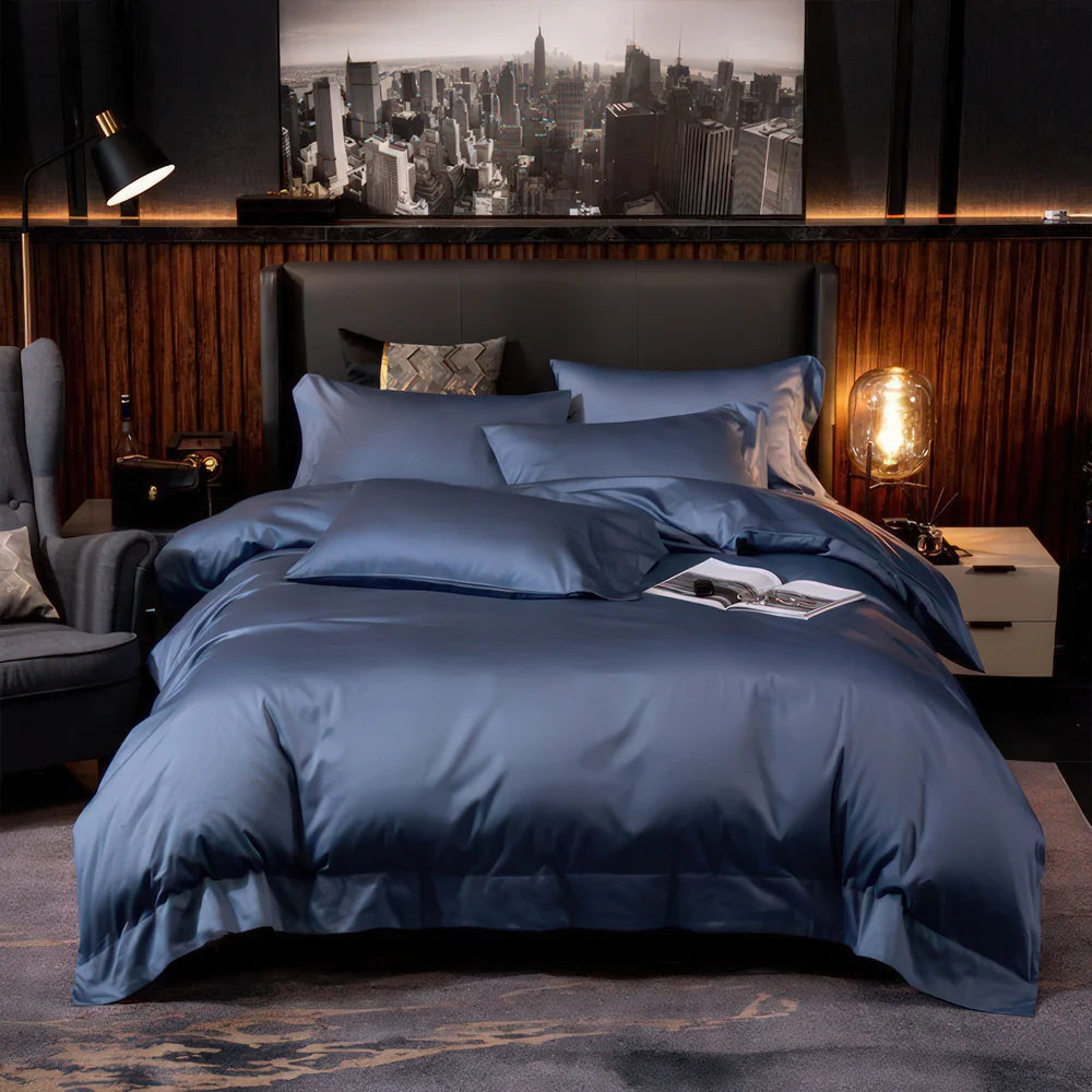 Modern bedroom with a blue satin bedding set featuring smooth, wrinkle-free fabric, accented by plush pillows and a black-and-white cityscape photograph above a dark leather headboard.

