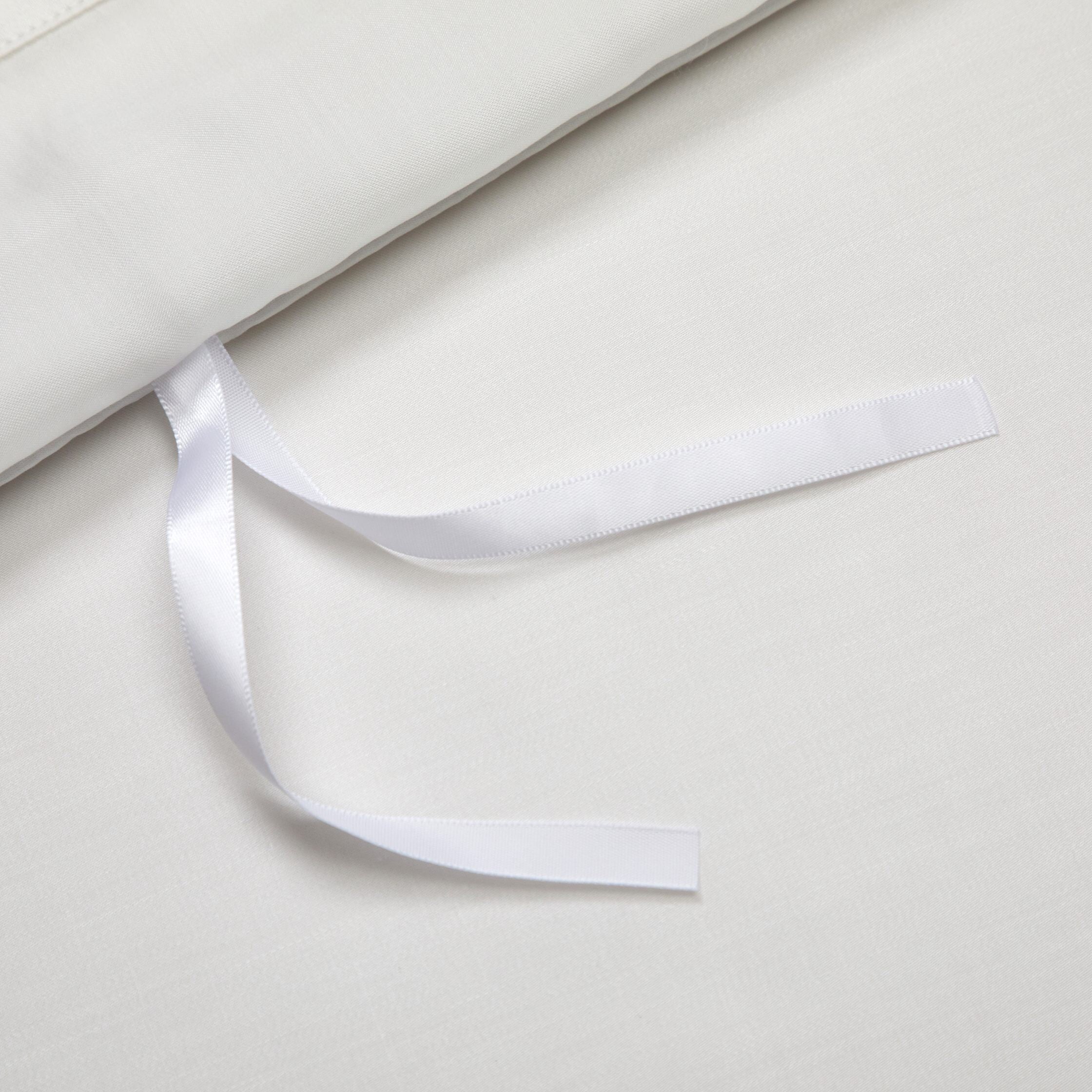 Close-up of an ivory-white fabric featuring a neatly attached white ribbon tie, designed for secure fastening or adjustable closure.