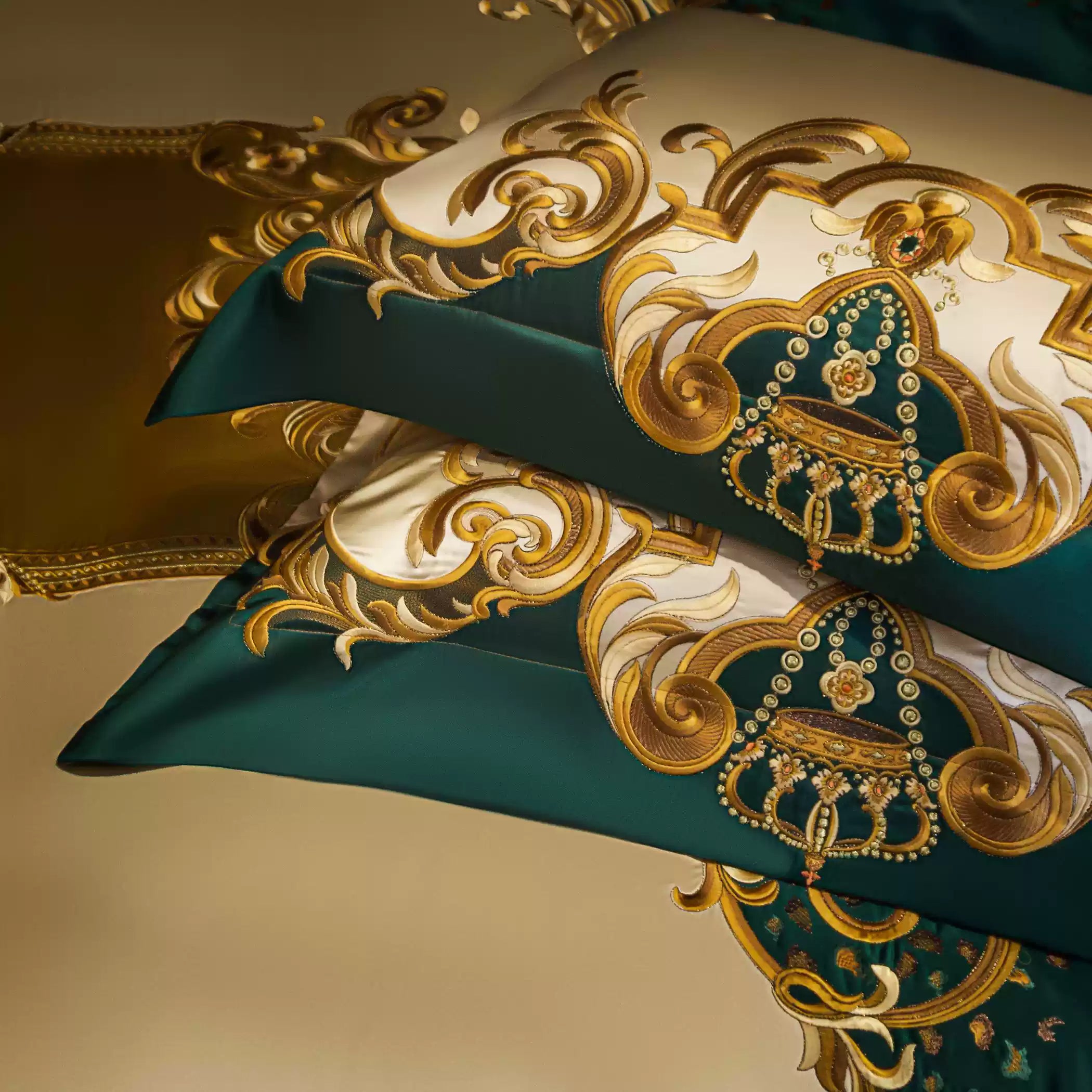 Close-up of decorative pillowcases featuring elaborate golden embroidery with emerald green accents. The luxurious design showcases baroque-inspired motifs, adding a regal touch to the bedding set.