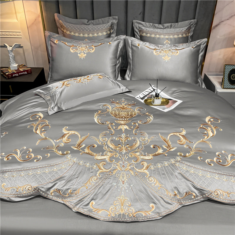 Grey bedding set with intricate gold baroque embroidery, showcasing ornate scrollwork, a regal central motif, and decorative patterns on the pillowcases and duvet cover. The fabric's smooth sheen enhances its luxurious appearance.

