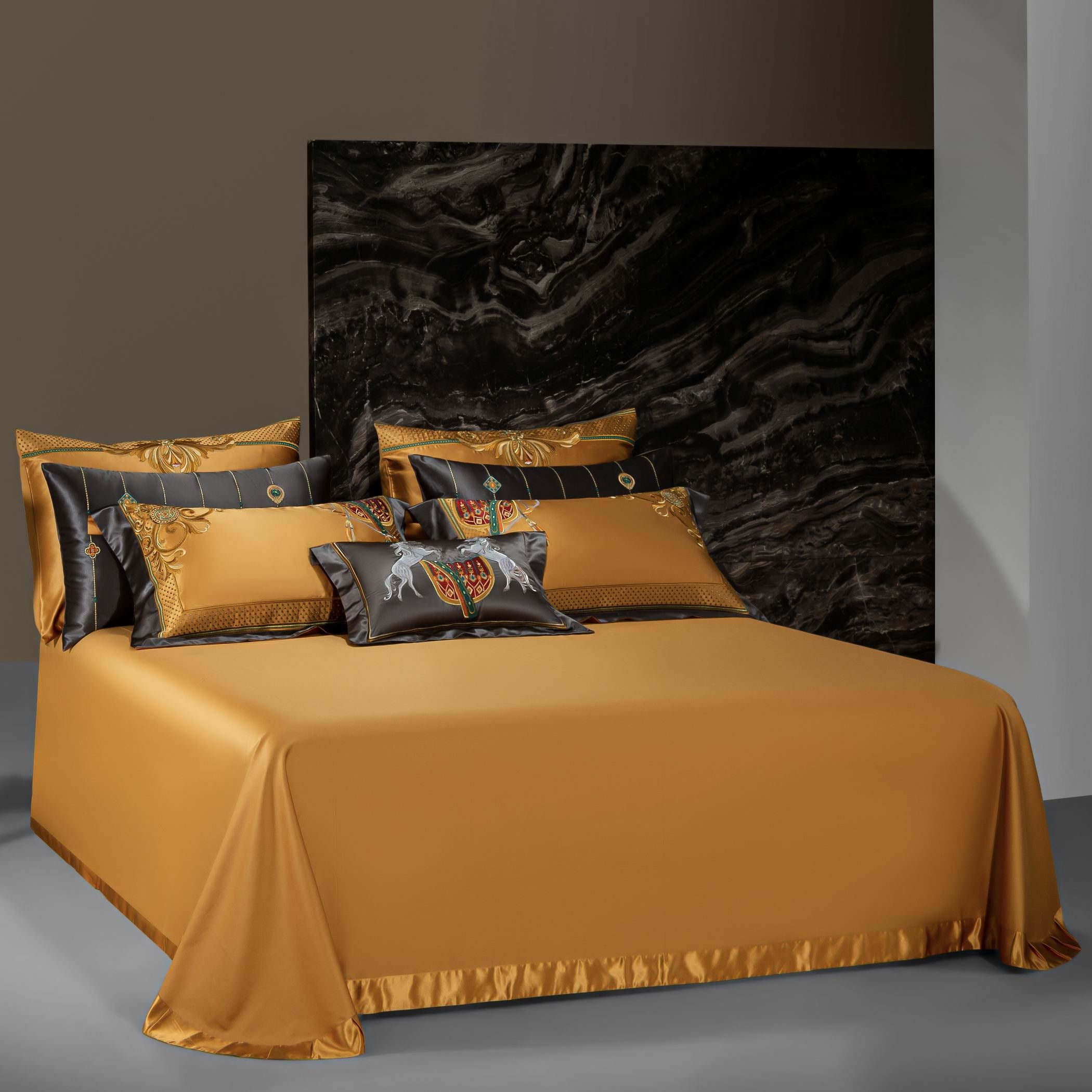 A luxurious bedding ensemble highlighted by a golden satin bedspread draping elegantly over the bed, accompanied by coordinating pillowcases and decorative pillows. The accent pillows showcase intricate black and gold embroidery, featuring regal designs such as rearing horses and ornate motifs. The dramatic black marble headboard creates a striking contrast, enhancing the warm and opulent golden tones of the bedding. The overall aesthetic is sophisticated, modern, and designed to elevate any bedroom space i