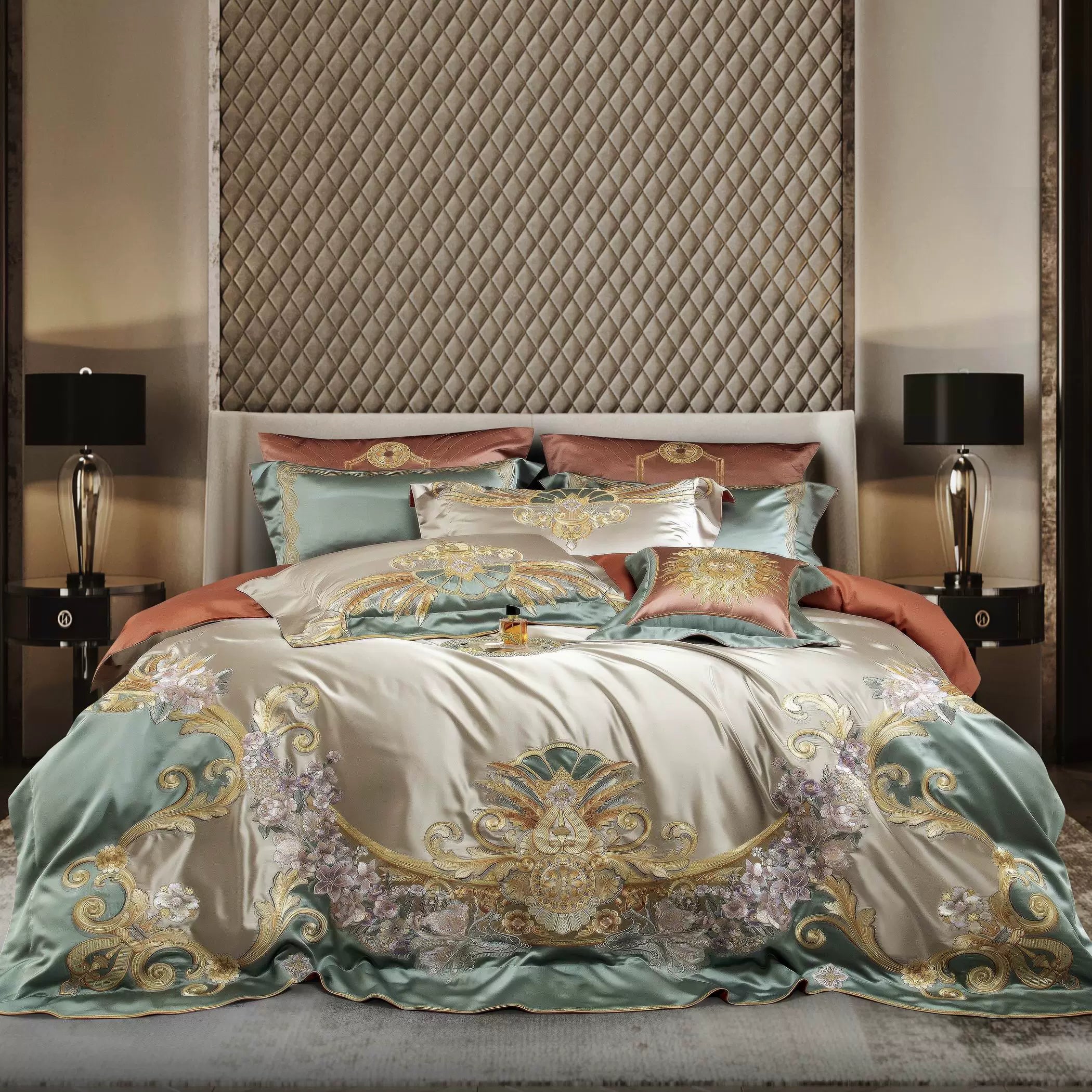 A luxurious bedding set showcasing an intricate design of golden embellishments and floral motifs on a satin fabric in hues of mint green and champagne. The layered pillows in complementary tones of terracotta and sage enhance the opulence. Framed by a diamond-quilted headboard and modern black bedside lamps, the setup exudes a refined and elegant ambiance, ideal for a premium bedroom.