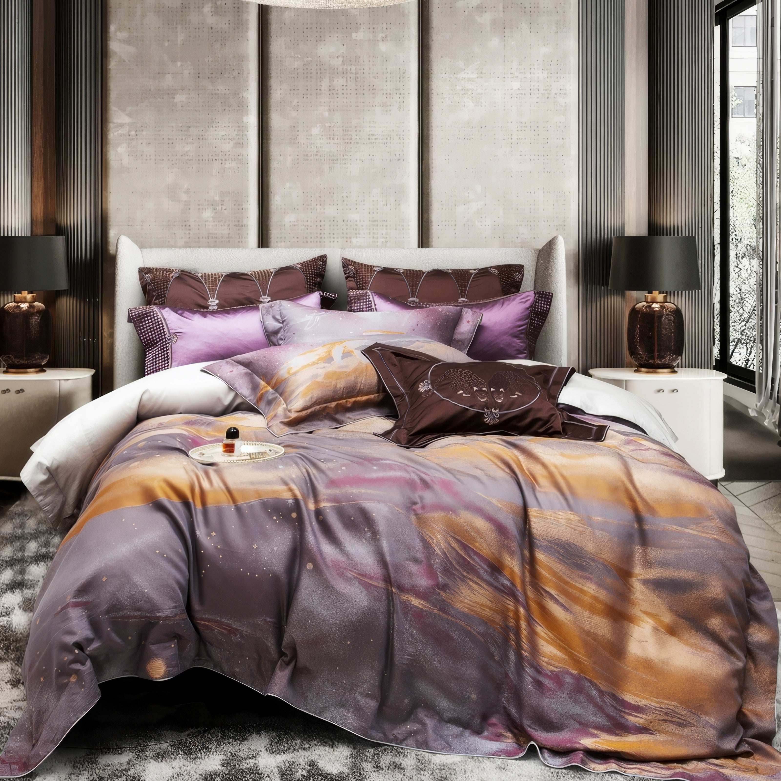 A luxurious bedding set featuring a blend of purple, gold, and grey hues in an artistic, abstract pattern. The setup includes matching pillowcases with intricate embroidery and complementary tones, along with decorative brown and purple accent pillows. The upholstered light-grey headboard and modern side tables with bronze lamps create a sophisticated and elegant bedroom ambiance, enhanced by a textured wall panel and a soft, patterned rug underfoot.