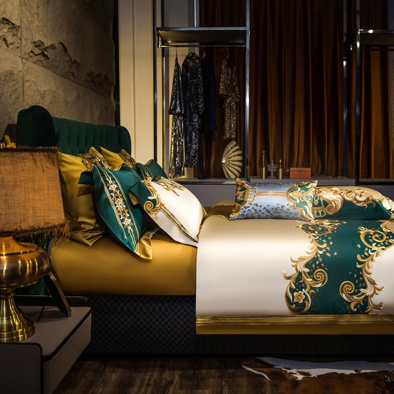 Side view of a luxurious bedding setup featuring golden and emerald green tones, complemented by intricate embroidery and baroque patterns. The background highlights a lavish dressing area, adding a touch of glamour and elegance to the scene.