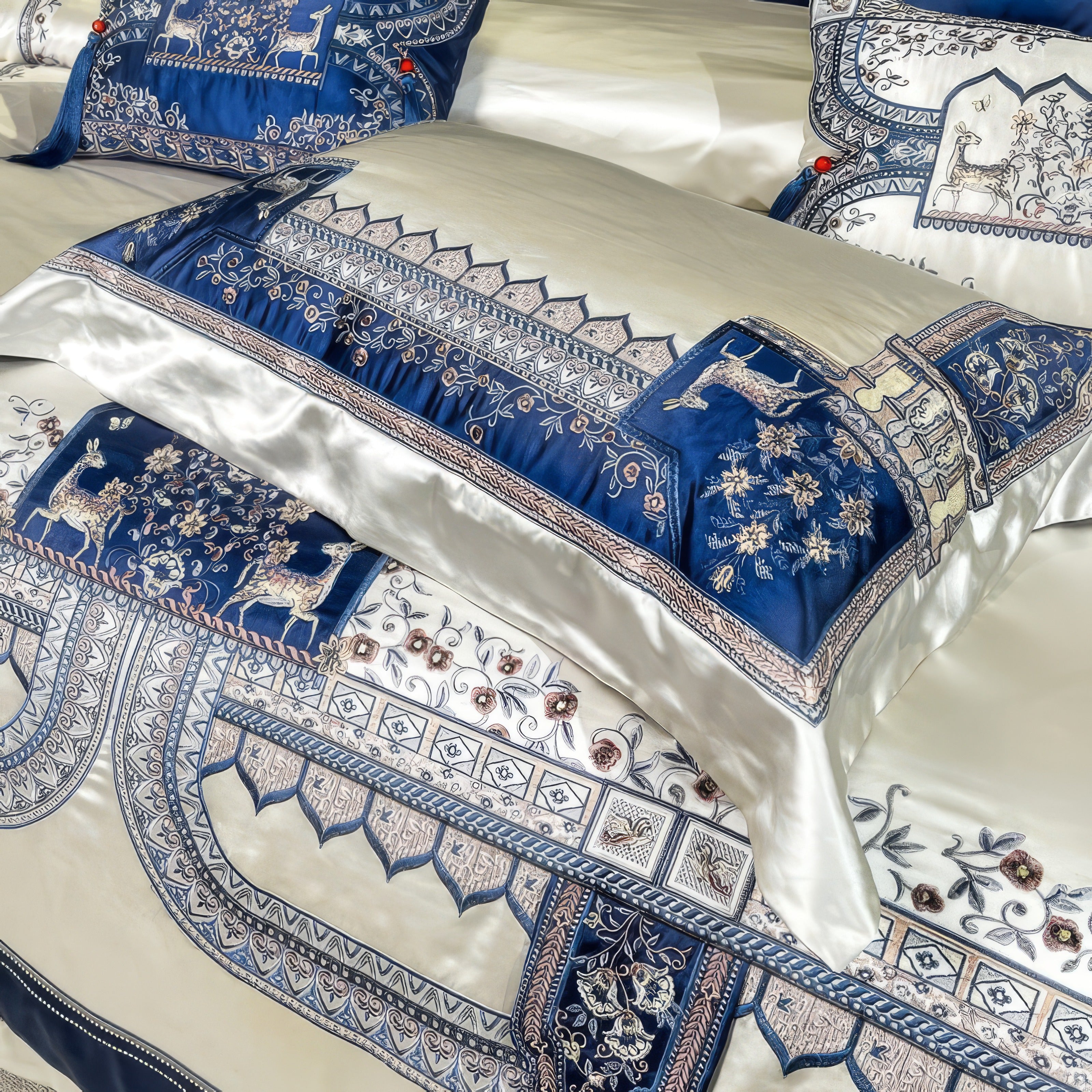 A close-up view of a luxurious silk bedding set featuring intricate embroidery in a royal blue and ivory color scheme, showcasing elegant patterns of deer, floral motifs, and ornate architectural-inspired designs, exuding sophistication and grandeur.