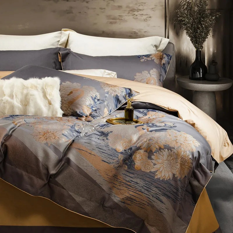 A side perspective of an elegant bedding set in dark gray, highlighted with golden floral patterns and swan motifs. The smooth, luxurious fabric features a gentle sheen, paired with a cream-toned flat sheet underneath. A white faux fur pillow adds texture and warmth, while a gold tray holds a decorative perfume bottle. The backdrop includes a modern bedside table and a vase of dried branches, adding a natural, contemporary touch to the sophisticated design.