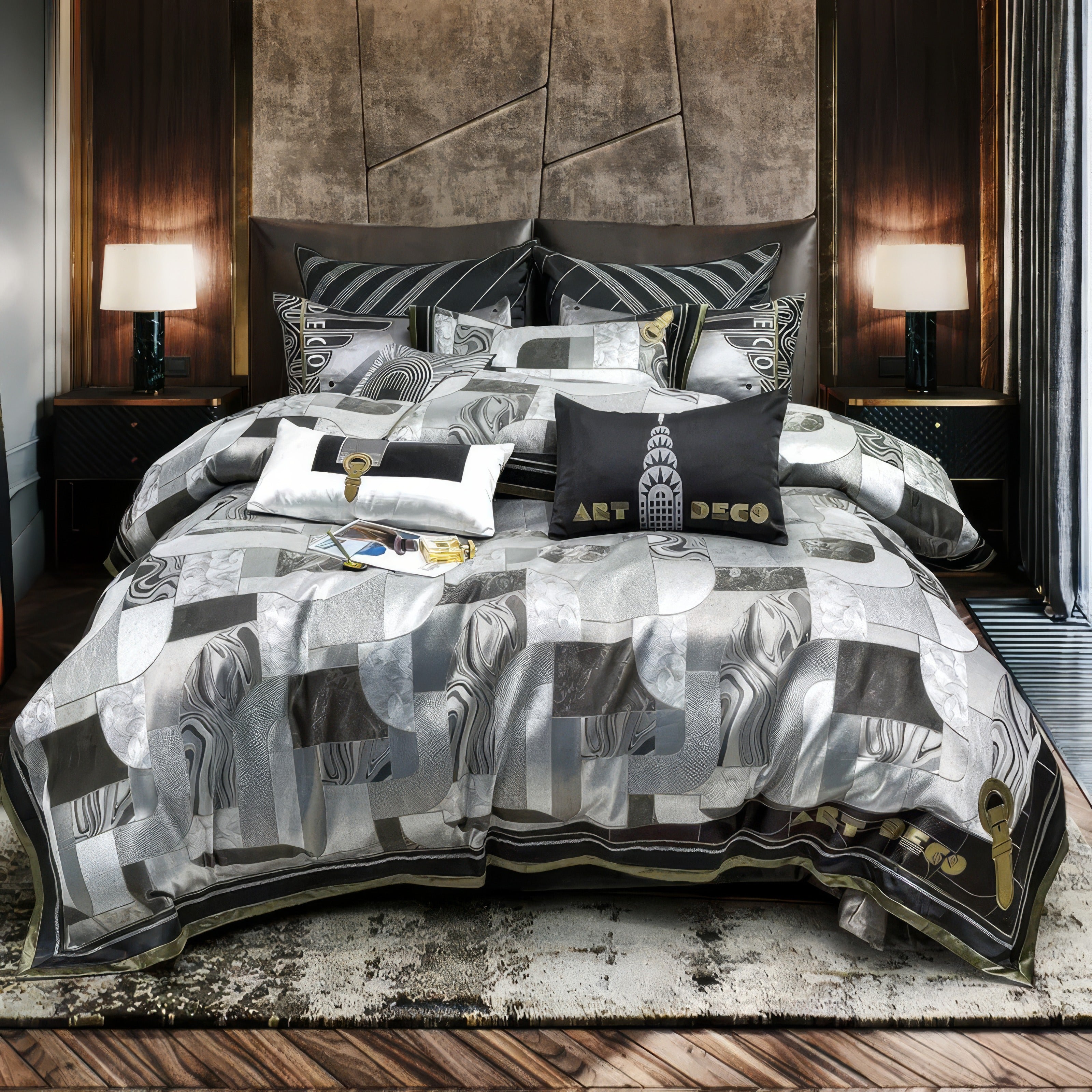 Luxurious Art Deco-inspired bedding set featuring a patchwork design in shades of silver, grey, and black. The bedding displays intricate geometric and marbled patterns, paired with complementary decorative pillows, including one embroidered with the phrase 'Art Deco' and an iconic building design. The sophisticated bedroom setup includes a modern bed frame, elegant nightstands with table lamps, and a textured area rug, exuding opulence and timeless style.