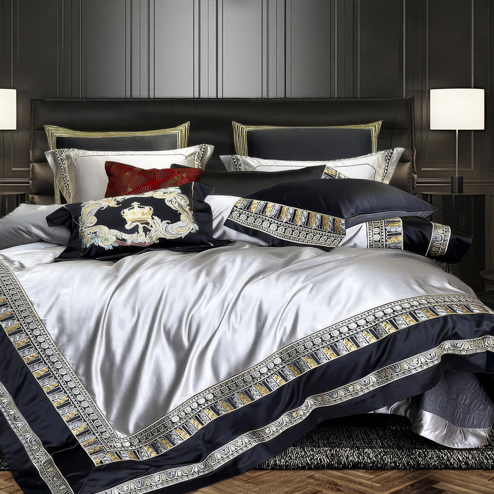 A luxurious bedding set crafted with a gleaming silver duvet cover, accented by bold black borders adorned with intricate gold geometric and floral embroidery. The accompanying pillows feature matching designs, including a standout black velvet pillow with a regal embroidered crest and a vibrant red decorative cushion. The set is staged in an opulent bedroom featuring dark wall paneling, modern lighting, and a rich, textured carpet, exuding an ambiance of contemporary elegance and aristocratic charm.

