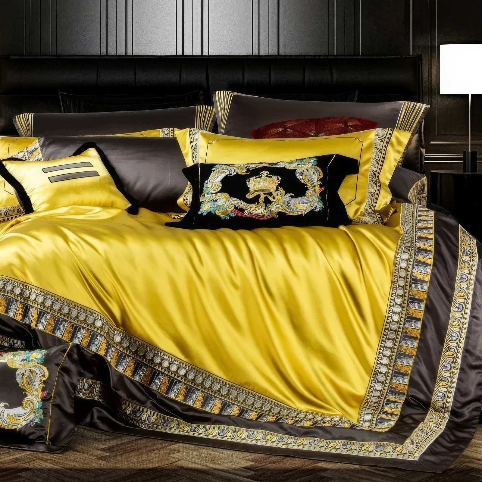 A close-up of a luxurious bedding set showcasing a vibrant yellow duvet bordered with elaborate black and gold embroidered patterns. The design is complemented by matching pillowcases in yellow and black, each adorned with intricate detailing. A standout decorative pillow with bold embroidery featuring a lion emblem in rich colors adds a regal touch, enhancing the opulent style of the set. The sheen of the fabric highlights its premium quality, exuding sophistication in a high-end bedroom setting.

