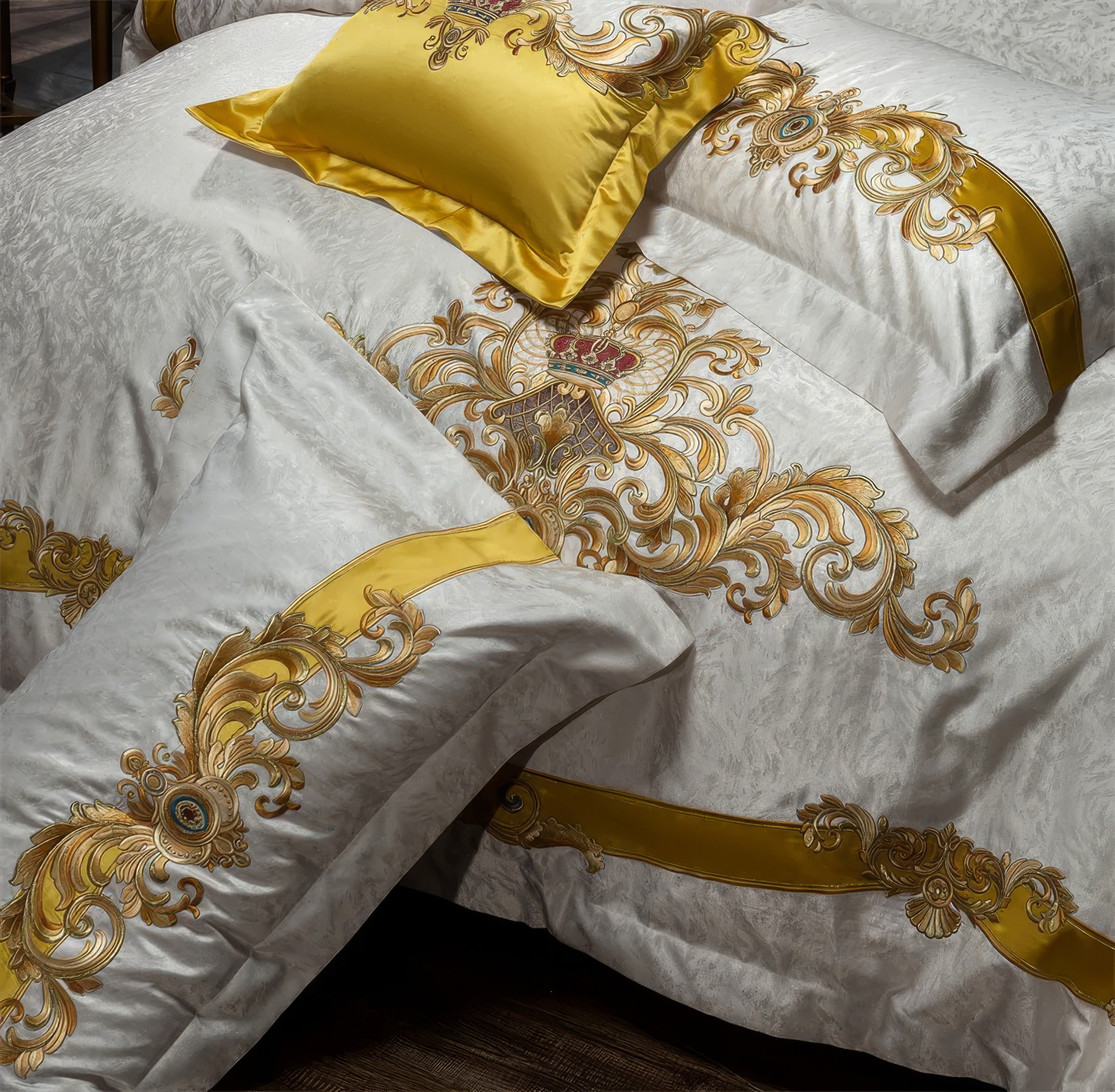 A detailed close-up of an opulent bedding set showcasing intricate golden embroidery against a luxurious white base. The design features baroque-style motifs with regal crown embellishments and ornate swirls, accentuated by a bold golden ribbon detail. The smooth texture and rich embroidery create a lavish and royal aesthetic, with the golden accent pillow adding a vibrant touch of elegance. Perfect for creating a majestic bedroom atmosphere.