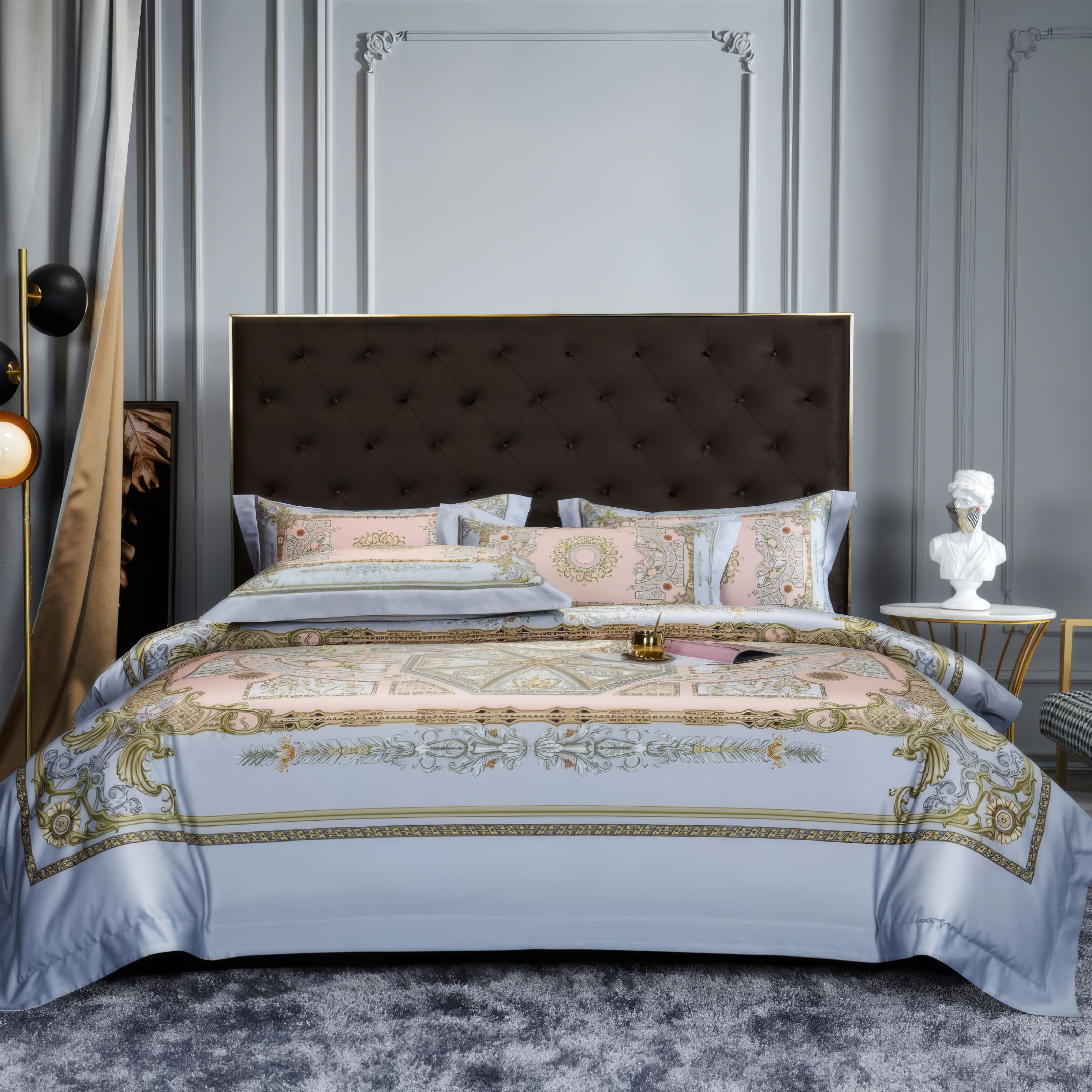 Elegant bedding set crafted from soft Egyptian cotton, featuring intricate gold and pastel pink patterns on a light blue base, styled with a tufted dark headboard and modern decor elements, including a white bust sculpture and contemporary lighting.

