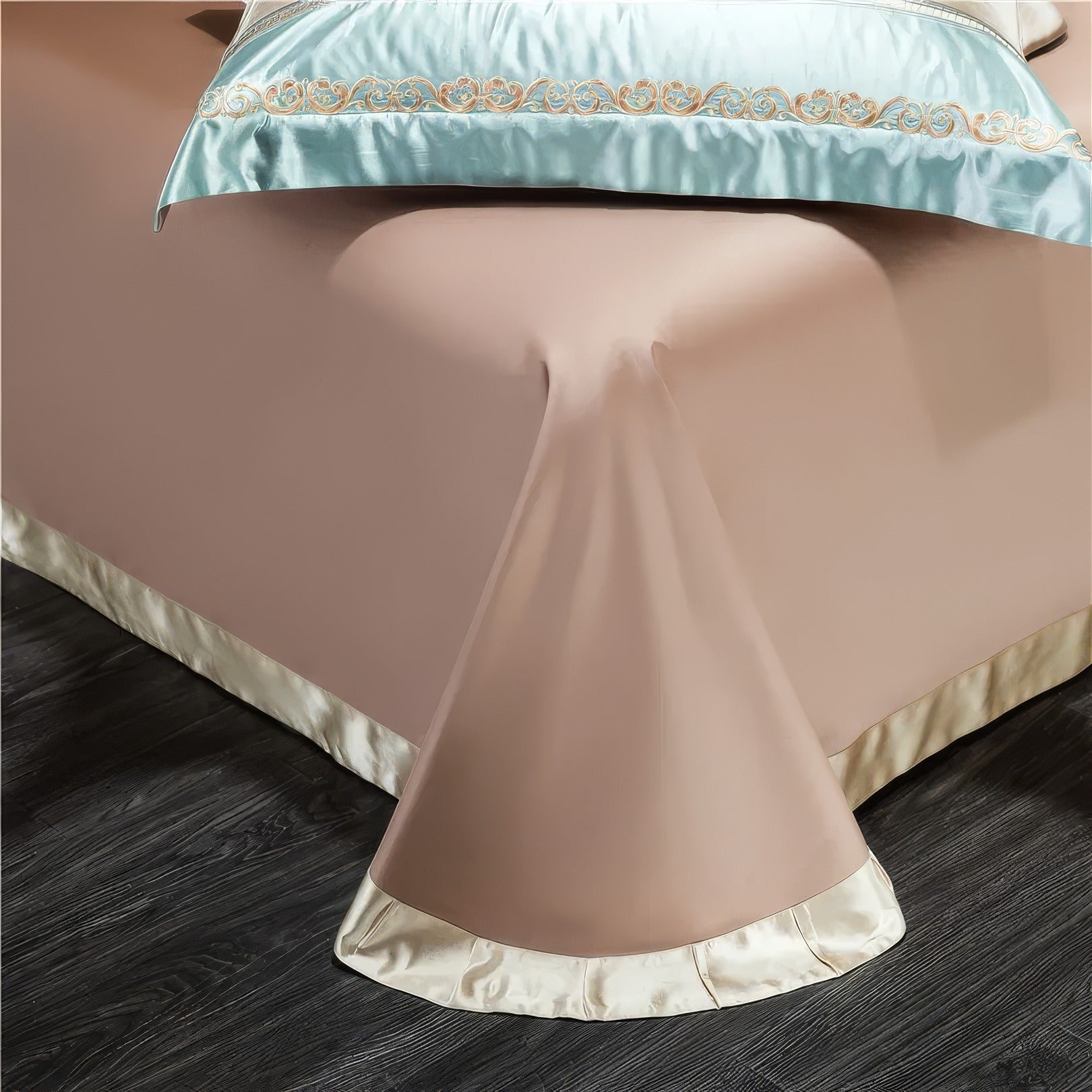 A detailed view of the lower corner of a luxurious beige bed skirt with a satin finish, elegantly draping to the floor. The edge features a contrasting cream trim, adding a sophisticated touch to the design.

