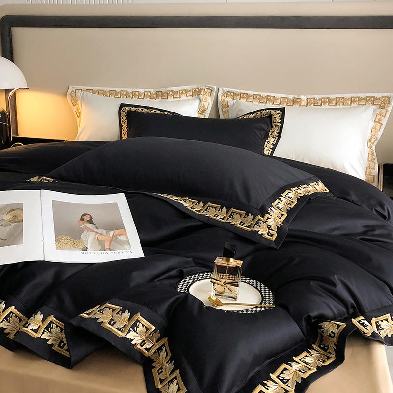 Luxurious black Egyptian cotton bedding with gold embroidered details, styled with a fashion magazine, perfume, and elegant tableware, evoking a sense of sophistication and elegance.

