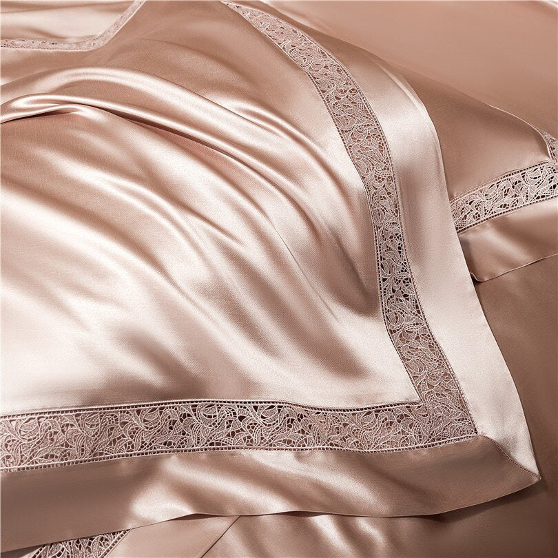 Luxurious champagne-colored satin bedding with a smooth and lustrous surface, elegantly bordered with intricate lace detailing. The fabric’s soft drape and reflective sheen highlight its premium quality and sophisticated design.