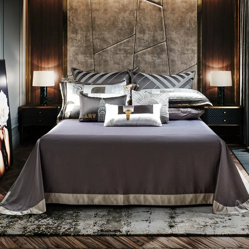 Elegant Art Deco bedding ensemble showcasing a minimalist sheet set in a rich gray tone with a sophisticated satin border. The backdrop features a modern textured wall and warm lighting, emphasizing the luxurious and contemporary appeal of the bedding.