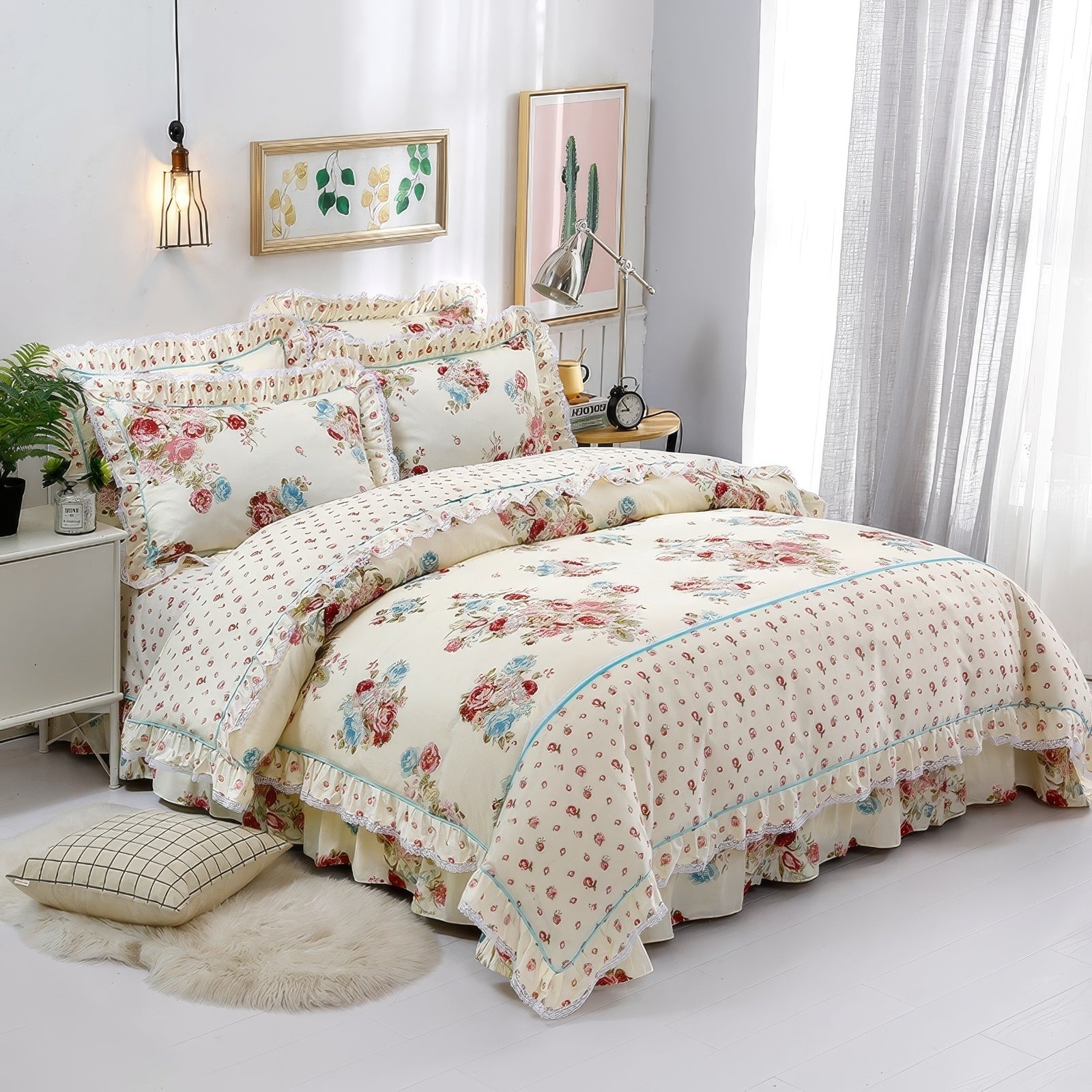 Cream floral bedding set featuring red, pink, and blue roses, complemented by lace-trimmed ruffles and a delicate polka dot pattern. The bed is styled with matching pillowcases and a layered duvet, creating a vintage aesthetic. A cozy room setup includes a beige rug, a grid-patterned pillow, plants, and framed botanical wall art, with soft light streaming through sheer curtains.

