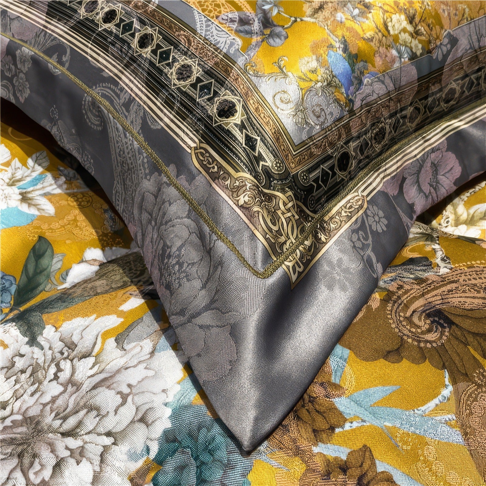 Close-up of luxurious bedding featuring golden floral patterns, intricate gray detailing, and colorful blue and white accents, highlighting the rich fabric texture and ornate design.

