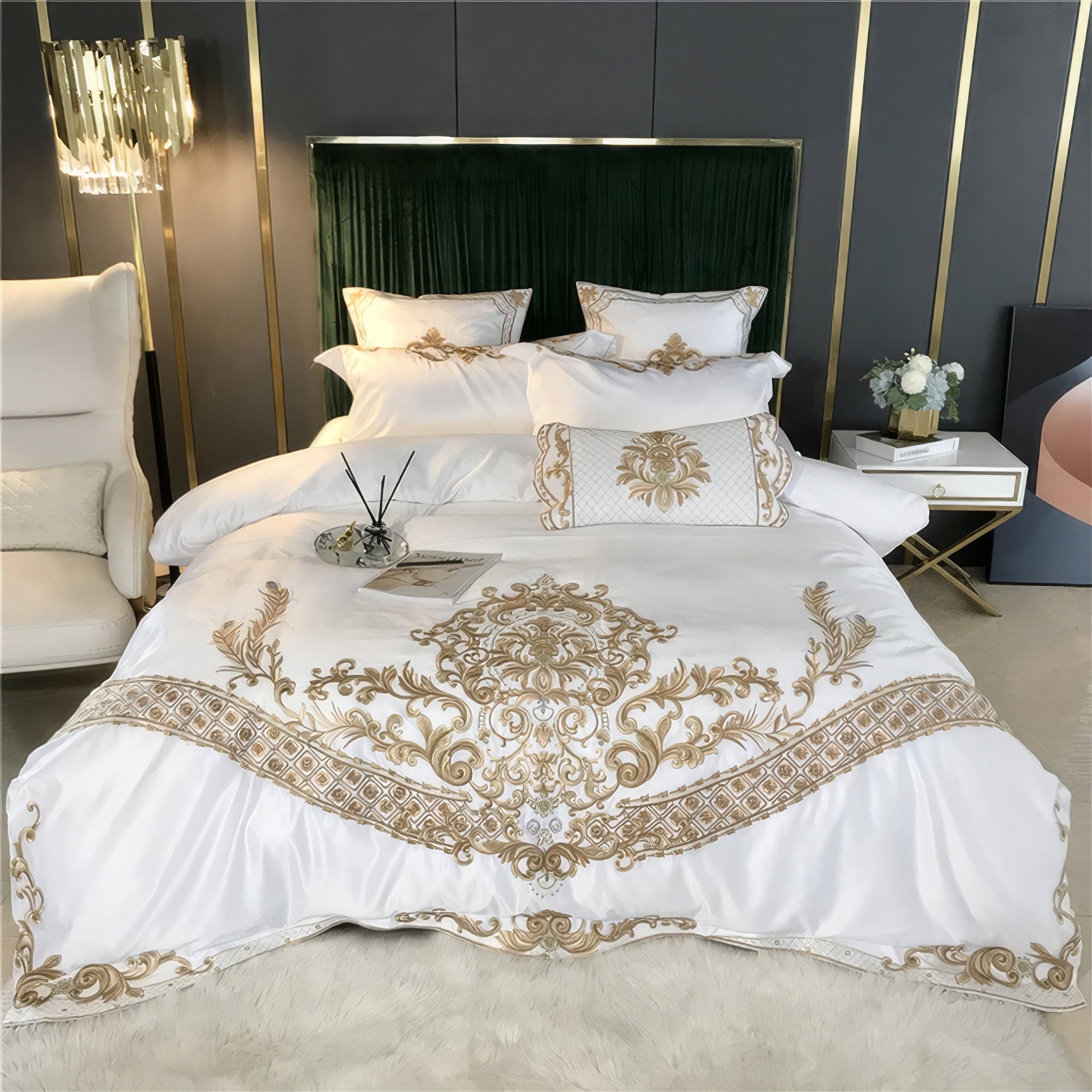 A luxurious white bedding set adorned with intricate gold embroidery, showcasing elegant baroque patterns. The ensemble includes matching pillows and a bolster with complementary designs, creating a sophisticated and opulent aesthetic. The bed is styled with a plush green velvet headboard and accessorized with a modern nightstand and a vase of white flowers for a refined bedroom ambiance.

