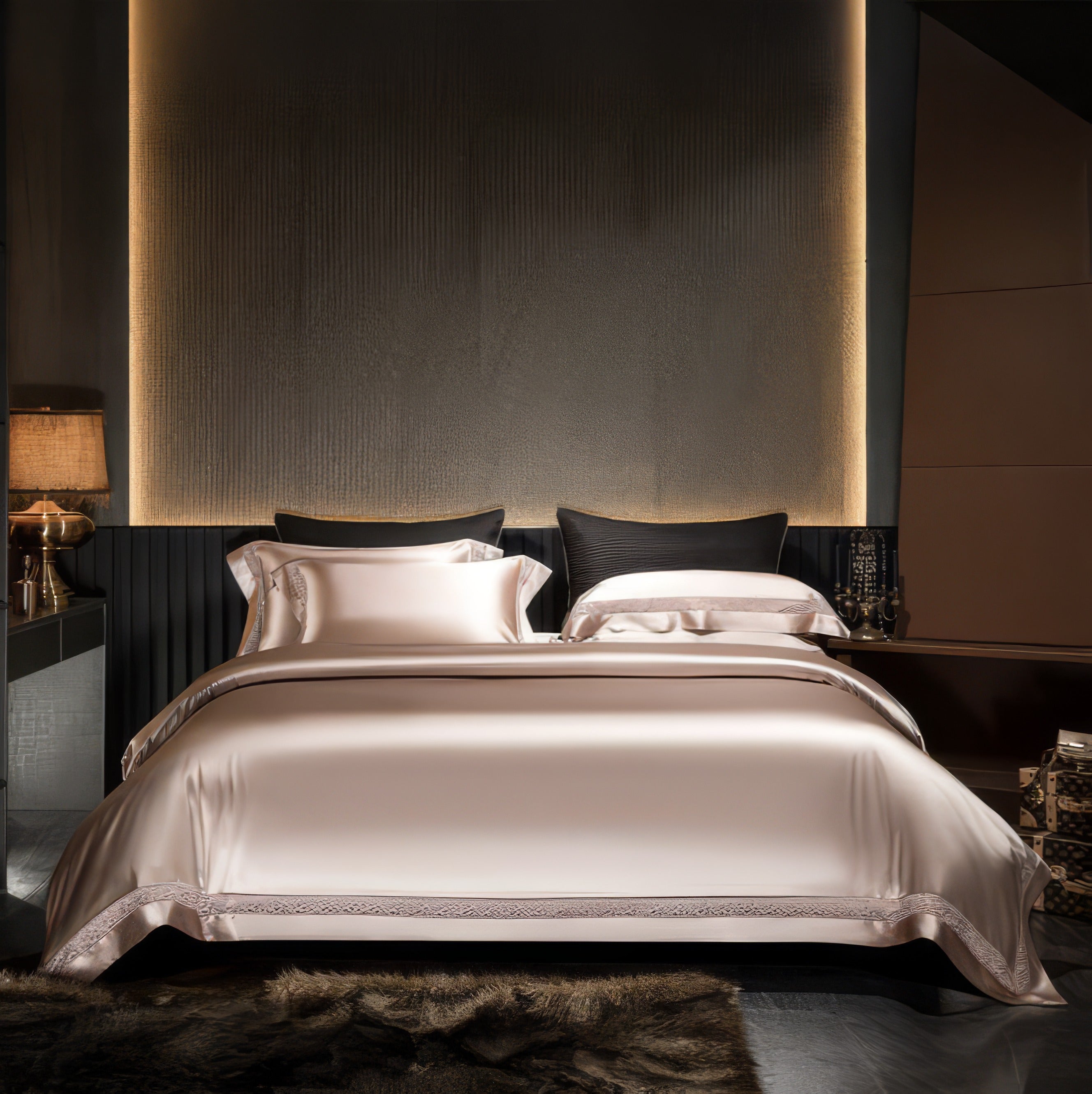 Luxurious bedroom setting featuring a satin bedding set in soft champagne hues. The bed is adorned with matching pillowcases and detailed lace trim on the edges. The dark, textured backdrop, ambient lighting, and gold accents create a sophisticated and cozy atmosphere.